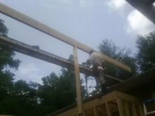 Carpenter setting a ridge beam over a new addition frame — Ice Dam Removal by Roofing Brothers in Danby