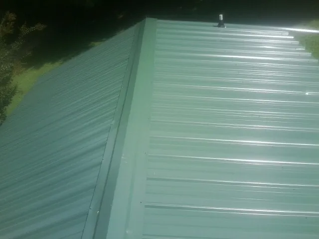 New green metal panels meeting at the ridge of a roof — Flat Roof Repair work by our crew in Danby