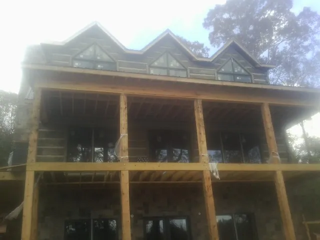 Dormers and porch framing on a large log home under construction — Roof Coating work by our crew in Danby