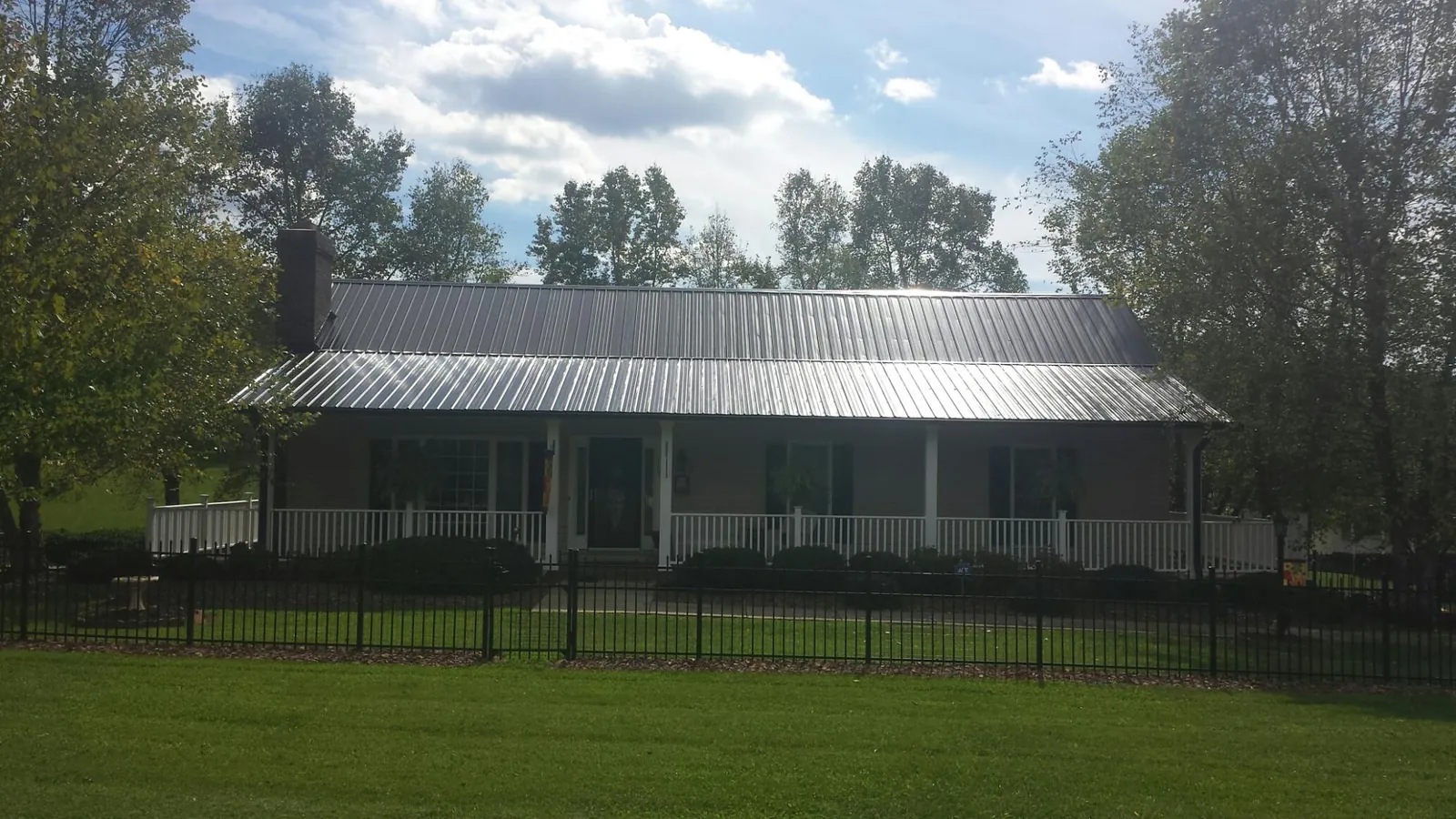 Gray metal roof on a brick ranch with a full width front porch — Gutter Guard Installation work by our crew in Danby