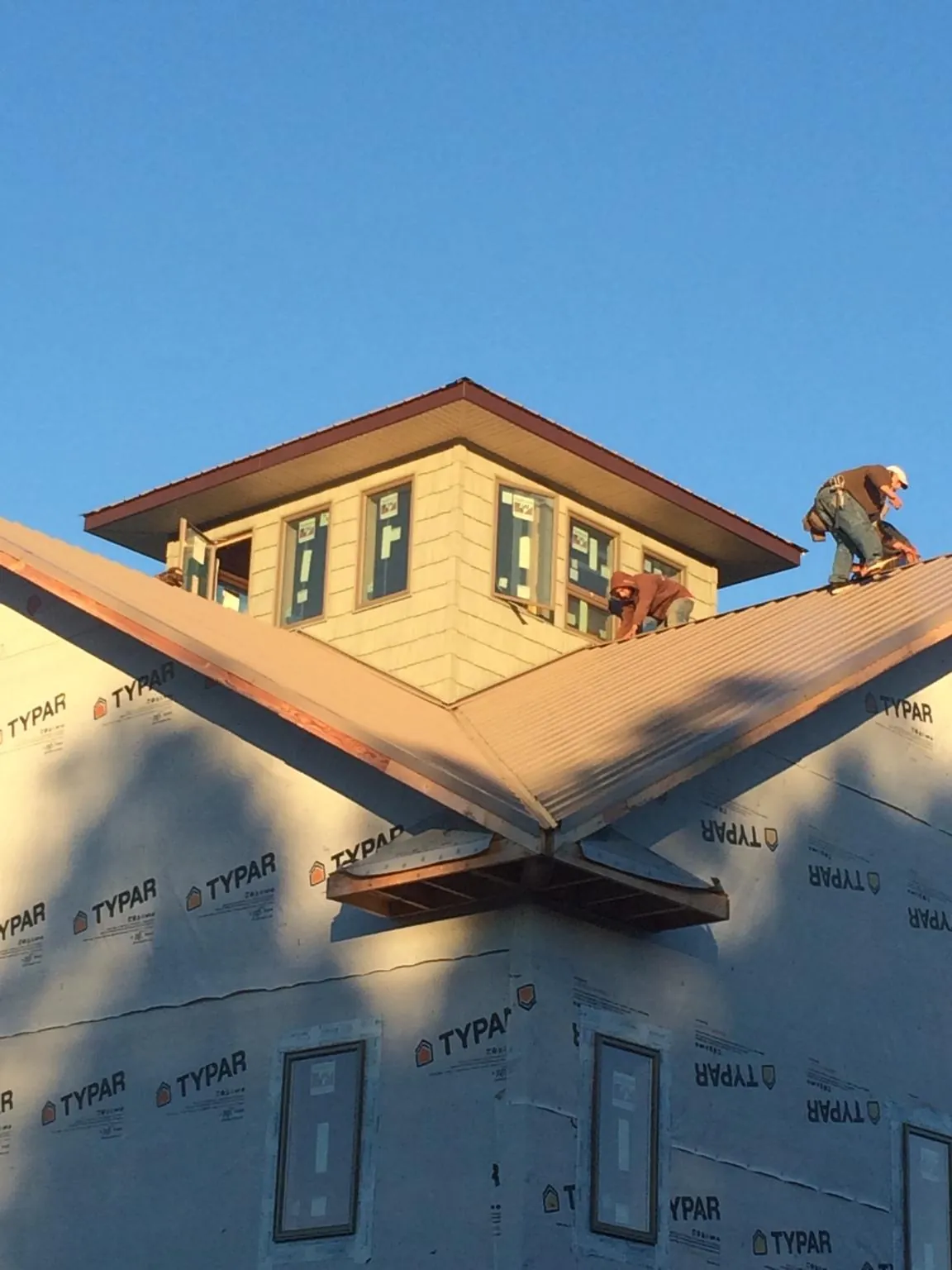 Roofers working around a rooftop cupola on a new metal roof at sunset — Roof Waterproofing in Danby by Roofing Brothers